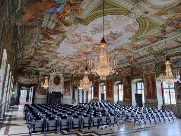 Im  Kaisersaal der Neuen Residenz, das wohl bedeutendste Raumkunstwerk der Bamberger Residenz, wurde von 1707 bis 1709 von Melchior Steidl (1657-1727) ausgemalt. Der große, aber niedrige Raum entfaltet seine enorme Wirkung durch eine illusionistische Erweiterung der Architektur in den Deckenhimmel. Am 21.09.2024 wird der Bamberger Domchor hier ein zu Ehren des 1000. Todesjahrs Kaiser Heinrichs II. ein Konzert zu Ehren des Heiligen geben
